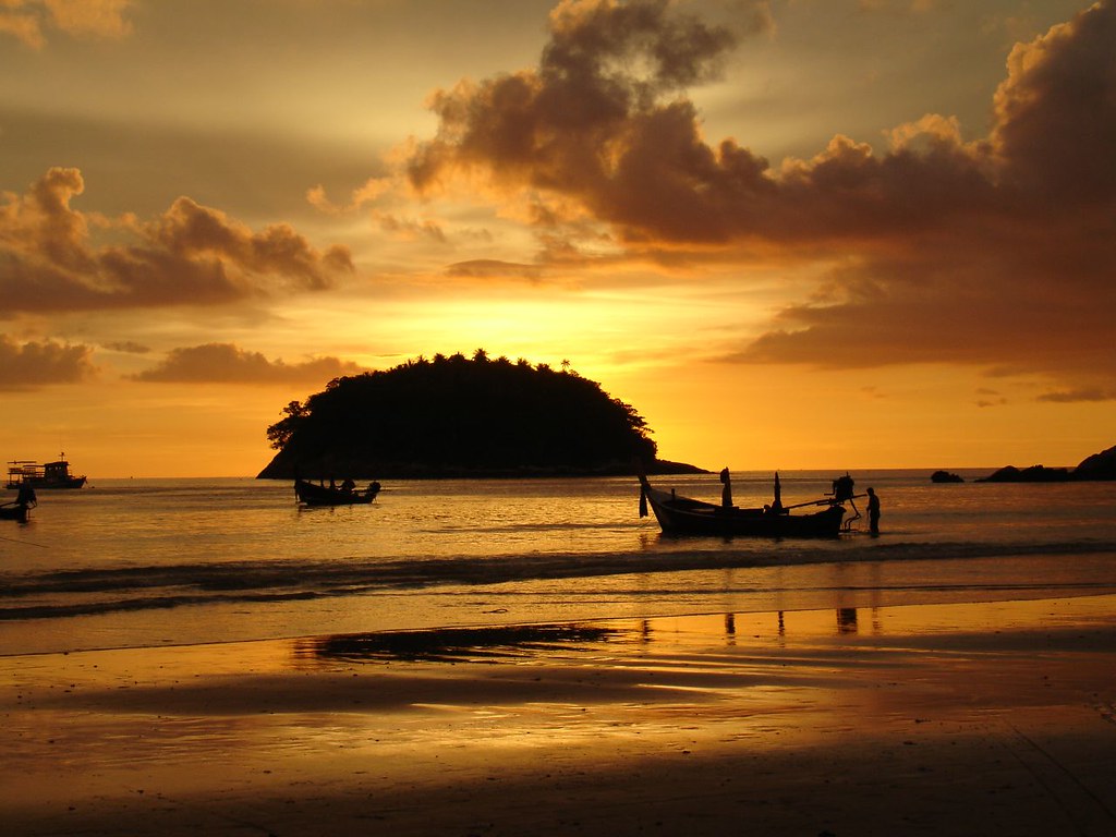 Golden sunset over Kata Beach, Phuket, with longtail boats